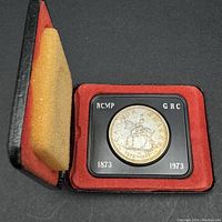 1973 Canadian silver dollar commemorative coin of RCMP 100 year anniversary, housed in black clamshell case with red velvet lining and foam padding in lid.