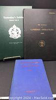 Three military hardcover books standing upright against a black background