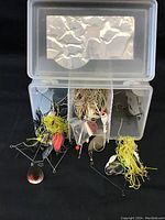 Plastic container with assorted used fishing lures and tangled fishing lines in multiple compartments.