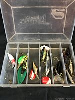 Photo of open tackle box showing compartments and variety of fishing lures including crankbaits and spinnerbaits.