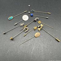 Top-down photo showing all stick pins spread on a dark surface with a quarter included for scale.