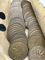 Close-up photo showing Canadian pennies dated 1956 featuring maple leaf design, coins in circulated condition.