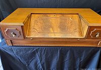 Front view of vintage tilt-top desk with closed writing surface and two side drawers.