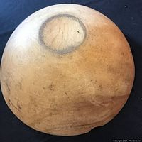 Bottom view of a vintage wooden bowl showing circular discoloration and wood grain.