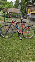 Full side view of red Millennium Extreme Shock mountain bike with rear black SportRack Frontier bike rack, showing overall condition and setup outdoors on grass.