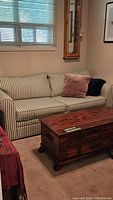 Full view of striped love seat in room with wooden coffee table in front