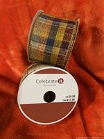 Two spools of wired plaid fall ribbon by Celebrate It, showing color and packaging details
