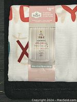 Photo of new folded white fabric shower curtain with holiday text design and packaging label.