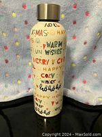 Front view of white insulated metal water bottle decorated with colorful holiday-themed words and graphics.