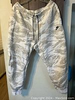 Front view of Nike pants in white and light gray camouflage print, hanging to show design and condition