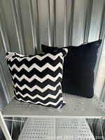 Photo showing one outdoor pillow with black and white chevron pattern and solid black back.