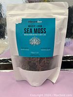 Front view of 57g white resealable pouch with blue label reading 'Vibrant Sea Wild St. Lucia Sea Moss'. Shows product inside through clear bottom area.