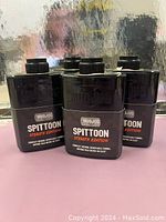 Front view of four black Mud Jug Spittoon Stealth Edition compact spittoons arranged in two rows.