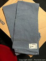 Two blue and white chevron patterned tea towels folded on cardboard, showing new condition and a price tag on one.