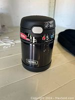 Front view of black Thermos food jar showing brand logo, capacity and heat retention information