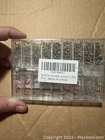 Photo of the back of the sealed plastic organizer box showing compartments filled with assorted tiny screws and a barcode label.