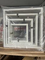 Set of 4 white nested square wall box shelves packaged in plastic, showing different sizes and inner dividers.