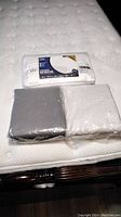 White quilted fitted mattress pad in packaging on mattress