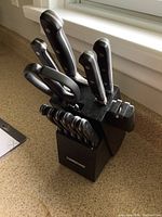 Farberware cutlery knife block with knives and scissors inserted, showing various blades and the built-in sharpener on the side.