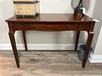 Front view of the wooden desk showing the drawer and condition of the finish.