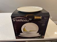 Front of the box showing the brand Trudeau and set contents of plates and bowls, 16-piece dinnerware set
