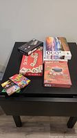 Photo of all games and puzzles displayed on a black table including magnetic chess board, Scrabble, Yahtzee, and UNO cards.