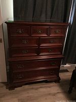 Front view of Gibbard dresser showing mahogany wood, seven drawers with brass handles, and glass top.