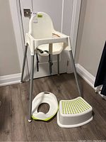 Ikea kids high chair, white plastic seat with metal legs, step stool, and potty seat on wood floor