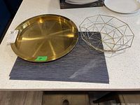 Overview of the metal tray, geometric metal bowl, and one placemat on a countertop