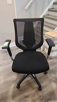 Front view of the black office chair with mesh back and adjustable armrests