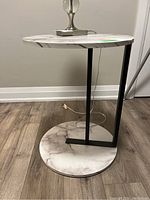 Front view of the side table showing the round laminated top and bottom with black metal frame