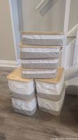 Eight stacked fabric storage bins with wooden tops, beige and white color scheme
