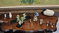 Overview of all animal figurines on wooden table including tin cats, mouse bookends, hedgehogs, and wrapped sheep