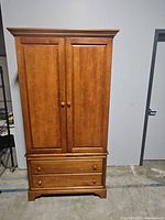Front view of closed wooden armoire with two doors and four drawers