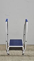 Front view of the AdjustaStep step stool against a plain background, showing white frame, blue platform and padded handles.