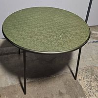 Top view of round green vinyl folding table showing surface texture and condition.