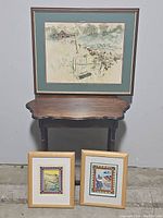 Three framed nature-themed artwork pieces displayed against a wall with a small wooden table underneath.