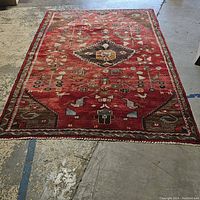 Full view of the large red rug spread on floor, showing overall design, size, and condition.