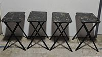 Group photo of the four vintage folding snack tables showing their matching black faux marble laminated tops and black folding metal legs.