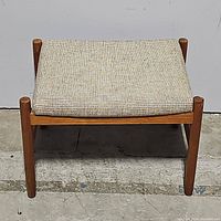 Front view of stool showing teak frame and upholstered seat
