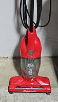 Red Dirt Devil 3-in-1 mini upright vacuum with clear dust bin and Quickpath base attachment.