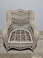 Front view of large white rattan wicker armchair showing woven design and wooden slat seat base.