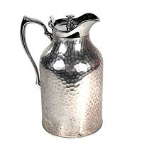 Front angled view of the hammered aluminium pitcher with handle and hinged lid.
