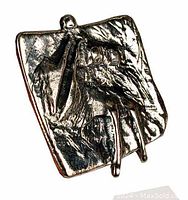 Front angle view of the cast pewter brooch showing raised abstract figure on textured rectangular base with patina.