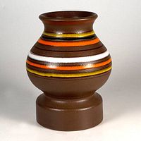 Front view of brown pottery vase with orange, yellow, white, and brown horizontal stripes and flared lip on a pedestal base.