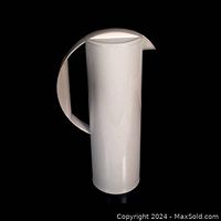 Front view of the tall pale grey plastic pitcher with handle and lid.