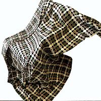 Full view of the wool tweed blanket draped, showing the alternating circle pattern across the fabric in moss green, tan, cream and black background.