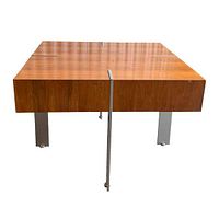 Angled side view showing thick walnut top with aluminium flat bar legs extending from top slots down to floor.