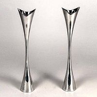 Pair of silver-tone modernist candlesticks standing side by side on a flat surface with a white background. Each has a flared base and tapered body with a flared top for holding candles.