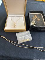 Lot of 10KY gold jewelry including pendants and fine rope chains, some with spring ring clasps and a lobster clasp accessory. One pendant features three vertically set bezel stones; the other is a two-tone butterfly.